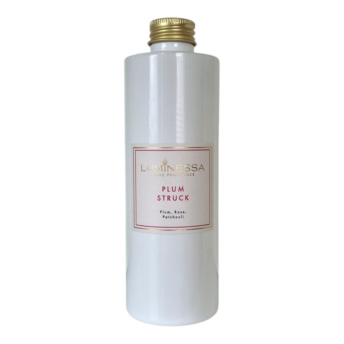 A white cylindrical bottle of Luminessa Plum Struck reed diffuser oil with a gold screw cap and a red and gold label, set against a plain white background.